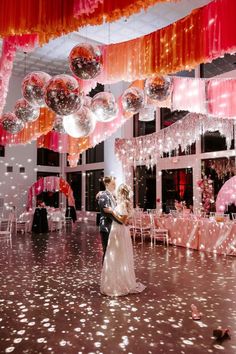 a bride and groom are standing in front of balloons on the dance floor at their wedding reception