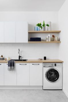 a clean kitchen with white cabinets and washer and dryer on the counter top