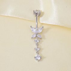 Get ready to spread your wings with the Dangling Butterfly Belly Button Ring! Made with durable 925 Sterling Silver, this 14 gauge navel ring features a charming butterfly with sparkling cubic zirconia gems. A delicate chain with more gems adds a touch of elegance. Keep an open mind (and belly button) and soar with style! Details: Waterproof & Tarnish-Free Made in responsibly sourced High-quality Solid 925 Sterling Silver for everyday wear. Stone: Extra-shine Cubic Zirconia Gemstones Gauge: 14G Navel Piercing With Chain, Butterfly Belly Button Piercing, Dangle Belly Button Piercing, Back Piercings, Ear Cuff Chain, Earring Cuff Chain, Barbell Earrings, Labret Piercing, Navel Ring