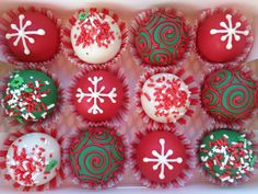 twelve red and green decorated christmas cupcakes in a white box with snowflakes on them