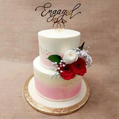 a three tiered cake with flowers on top and the word engaged spelled in cursive writing