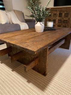 a wooden table sitting on top of a carpeted floor next to a gray couch