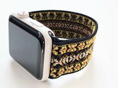 an apple watch band made out of multicolored knitted fabric with white buttons