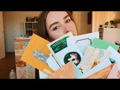 a woman holding up many different envelopes in her hands