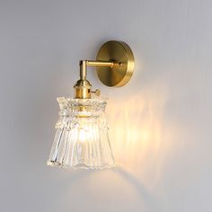 a light that is on the side of a wall next to a white wall with a glass shade