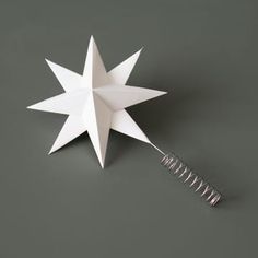 a white origami star on a gray surface with a metal spiral in the middle