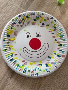 a paper plate with a clown face painted on the side and sprinkles all over it