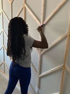 a woman standing in front of a wall holding a paint roller and painting the walls