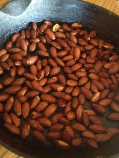 almonds frying in a pan on a wooden table