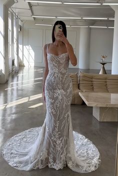 a woman taking a selfie wearing a wedding dress in the middle of a room