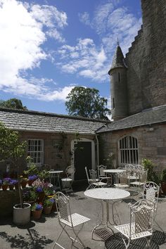 an outdoor table and chairs in front of a castle like building with potted plants