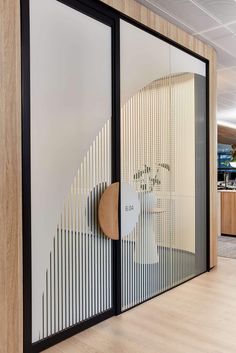 an office with glass doors and wood accents on the walls, along with a wooden clock