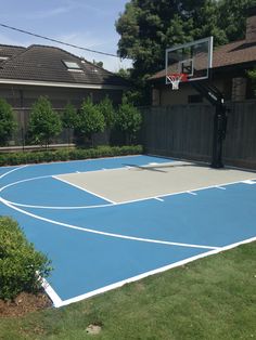 an outdoor basketball court is shown in this backyard area with grass and shrubs around it