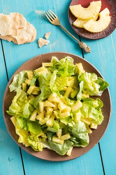 a plate full of lettuce next to some sliced apples on a blue table