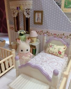 a doll house bedroom with a bed, dresser and toy rabbit on the floor next to it