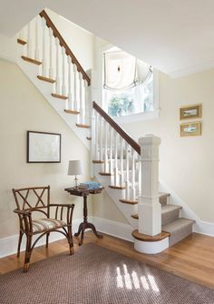 there is a chair and a table in the room by the stairs that lead up to the second floor