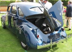 an old blue car with its hood open