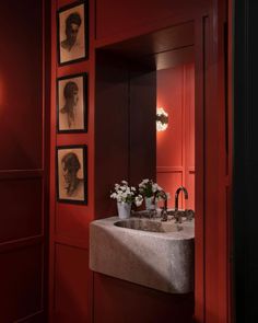 a sink in a red bathroom with pictures on the wall