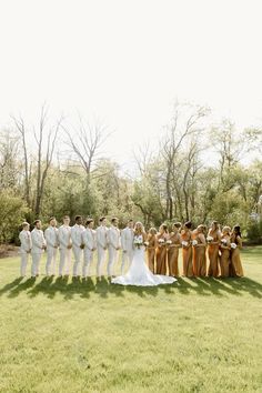 a large group of people standing on top of a grass covered field next to each other