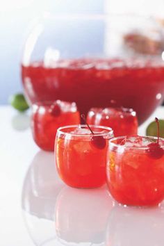 three glasses filled with liquid and garnished with cherries