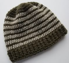 a crocheted beanie is shown on a white surface with grey and green stripes