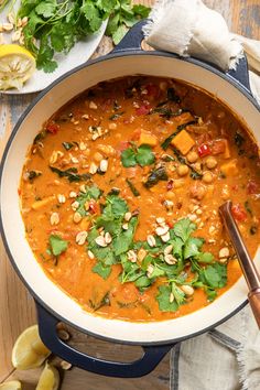 a large pot filled with soup and garnished with cilantro, pine nuts, parsley