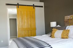 a bedroom with yellow sliding barn doors and white bedding in front of a wooden headboard