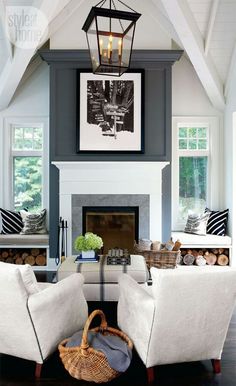 a living room with two white chairs and a fire place in the middle of it