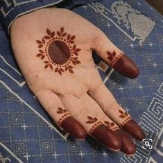 a woman's hand with henna on it and an orange circle painted on the palm