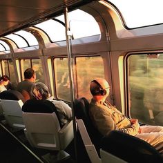 people sitting in seats on a train looking out the window