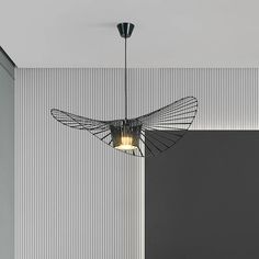 a modern light fixture hanging from the ceiling in a room with vertical striped wallpaper