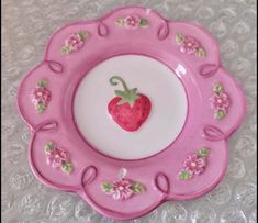 a pink and white plate with a strawberry on the center is sitting on a table