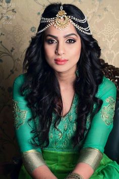 a woman wearing a tiara and green dress sitting down with her hands on her knees