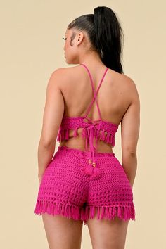 the back of a woman wearing pink crochet shorts and a halter top