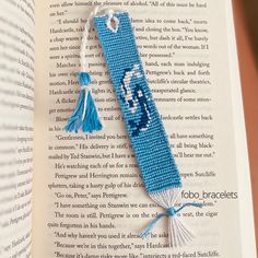 an open book with a blue and white beaded bookmark on top of it