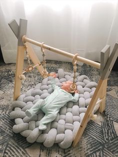 a baby is laying down in a swing made out of rocks and wooden posts with chains