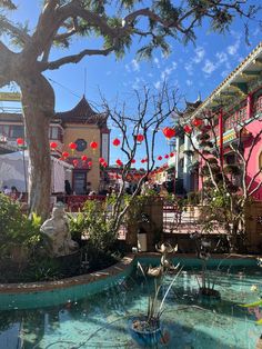 a small pond with red lanterns hanging from it's sides in front of a building