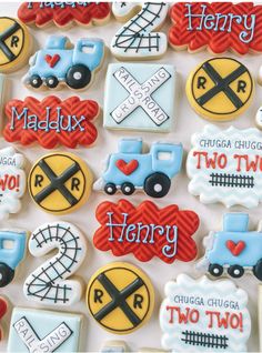 decorated cookies in the shape of trains and railroad tracks are displayed on a white surface