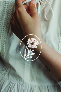 a woman's arm with a white flower tattoo on the left side of her arm