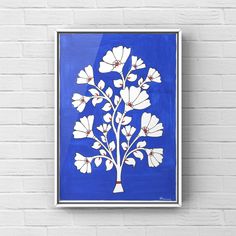 a blue and white painting on a brick wall next to a vase with flowers in it