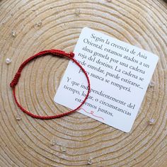 a red string bracelet on top of a piece of paper next to a small card