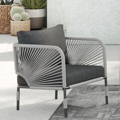 a gray chair sitting on top of a rug next to a potted cacti