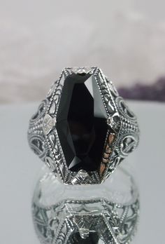 Black CZ Ring Description  Hexagon Design#237 MADE TO ORDER Here we have an Art Deco reproduction ring in sterling silver filigree with a perfect Black CZ gemstone solitaire. This faceted hexagon-shaped gem is 15mm in length and 13mm in width. This ring also sits 9mm off the finger. The inside of the band is marked 925 for solid sterling. Notice the beautiful geometric design of the silver filigree setting and etched band. This is a lovely rendition of an Antique filigree ring, and it is ready t Hexagonal Ring, Edwardian Jewelry, Art Deco Movement, Hexagon Design, Black Onyx Ring, Sterling Silver Filigree, Silver Art, Filigree Ring, Blue Sapphire Rings