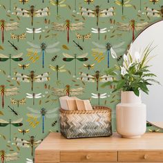 the wallpaper has dragonflies on it and is next to a vase with flowers