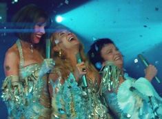 three women in sequins singing into microphones and confetti falling from the ceiling