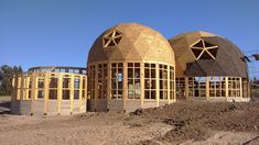 two large round wooden structures sitting on top of a dirt field