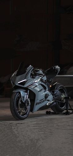 a silver motorcycle parked in front of a building at night with its lights turned on