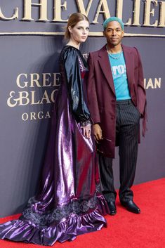 a man and woman standing next to each other on the red carpet at an event