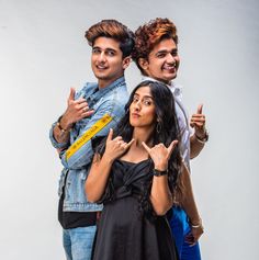 two men and a woman posing for the camera with their fingers up in front of them