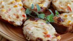 four pieces of bread with cheese and vegetables on it sitting on a plate next to a fork